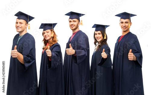 education, graduation and people concept - group of happy graduate students in mortar boards and bachelor gowns showing thumbs up over white background