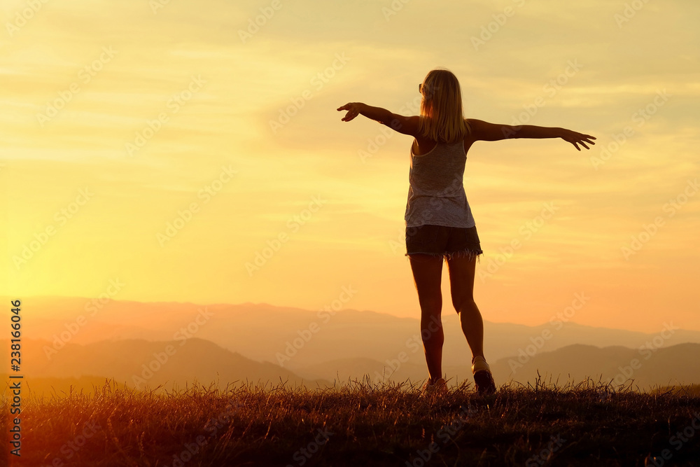 Happy woman with open arms stay on the peak of the mountain 