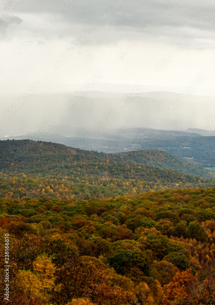 fall color forest and rolling hills and valleys in the Appalachians of Virginia with rain and clouds in the distance
