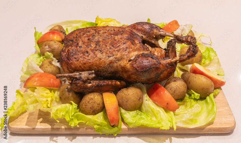 Christmas goose whole roasted and crispy on the cutting board with roasted potatoes, apples and brussels sprouts. Christmas goose whole roasted and crispy on the cutting board with roasted potatoes, apples and brussels sprouts.