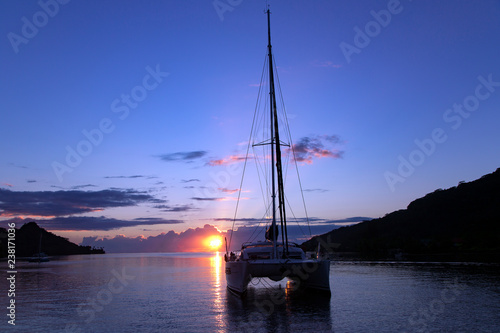 Lonely catamaran in a quiet lagoon near the island of Bora Bora at sunset in French Polynesia photo