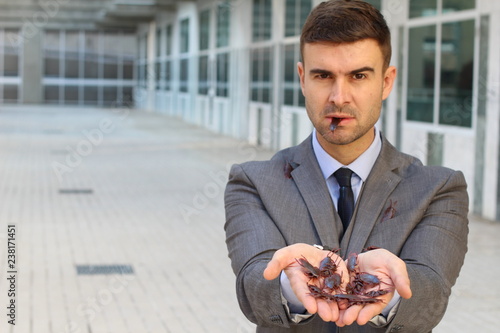 Businessman holding and eating roaches