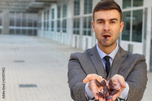 Bizarre businessman eating roaches at work