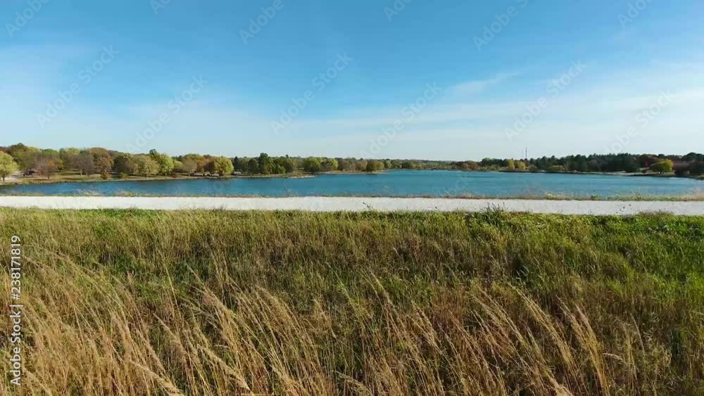 Aerial view up and over tall grass to wide lake Aerial view up and over tall grass to wide lake