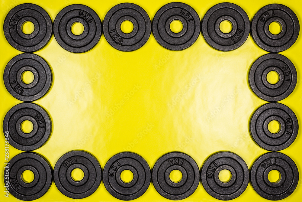Frame made from black metal weights 1kg on yellow background with copy sapce. Frame made from black metal weights 1kg on yellow background with copy sapce.