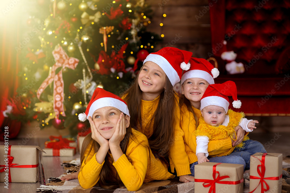 Children smiling in red hats on the background of the Christmas tree Children smiling in red hats on the background of the Christmas tree