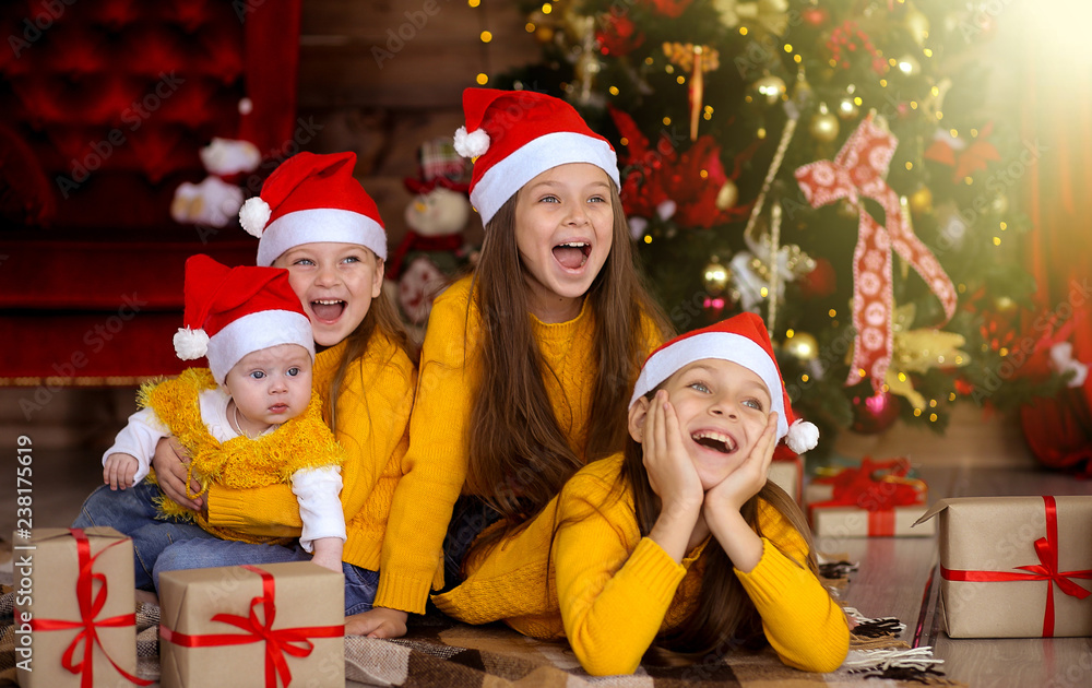 Children smiling in red hats on the background of the Christmas tree Children smiling in red hats on the background of the Christmas tree