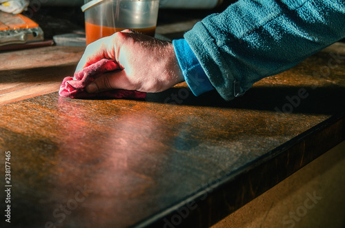 Carpenter covers wood furniture parts with wood wax photo