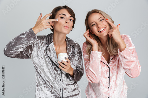 Two cheerful girls wearing pajamas standing