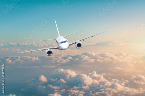 Passenger airplane flying above overcast clouds green pink gradient sky