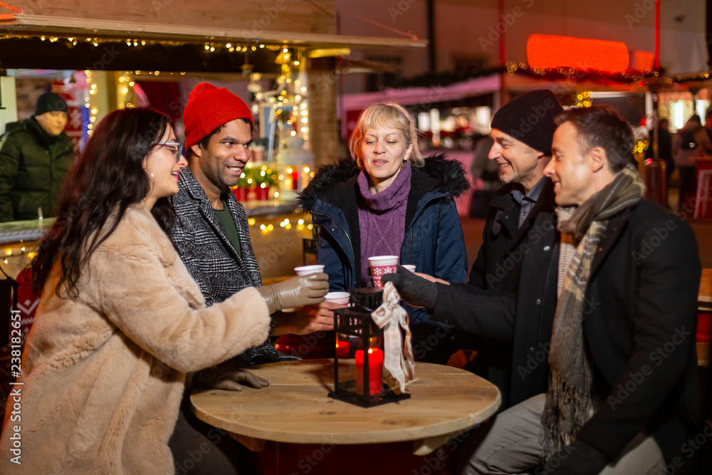 Group of friends cheering with traditional drink at Christmas market.