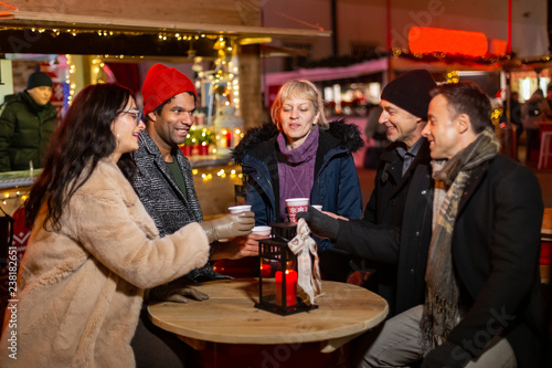 Group of friends cheering with traditional drink at Christmas market.