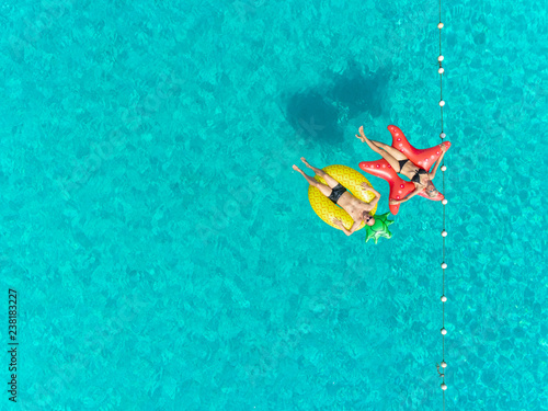 Aerial view of man and woman floating by string buoy on inflatable mattresses. © paul prescott