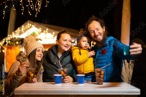 Father taking selfie with family at traditional Christmas market.