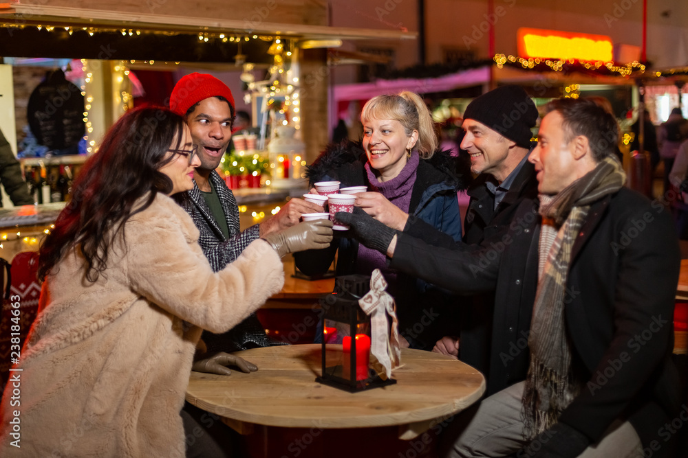 Group of friends laughing and cheering at Christmas market.