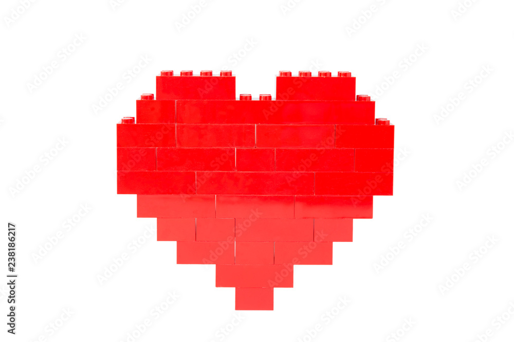Fototapeta premium Red heart made of toy building bricks, viewed from the front. Isolated on white background.
