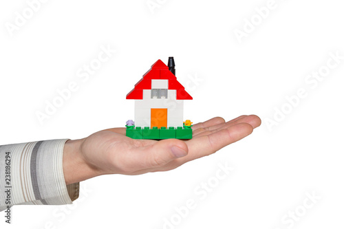 Man holding a small and simple house made of toy building bricks on his palm. Isolated on white background. Concept photo of real estate business or house ownership.