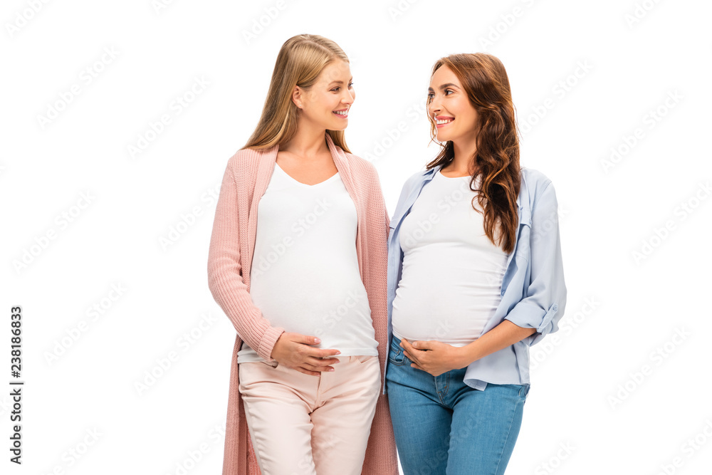 Naklejka premium two pregnant adult women smiling each other isolated on white