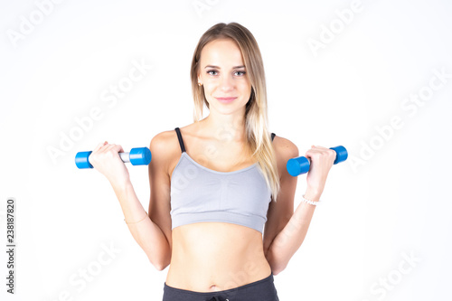 Beautiful young slim girl with dumbbells on a white background. Novice athlete