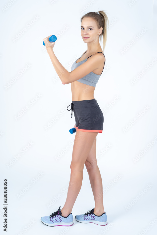 Beautiful young slim girl with dumbbells on a white background. Novice athlete Beautiful young slim girl with dumbbells on a white background. Novice athlete
