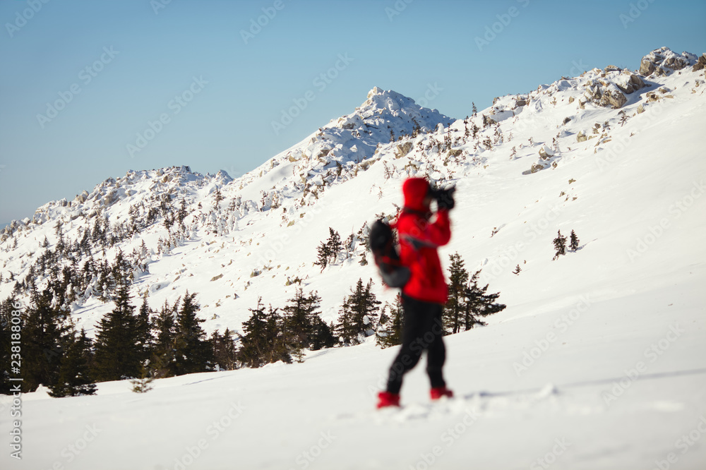 Blurred silhouette of the photographer on a background of snow-covered mountain range.
