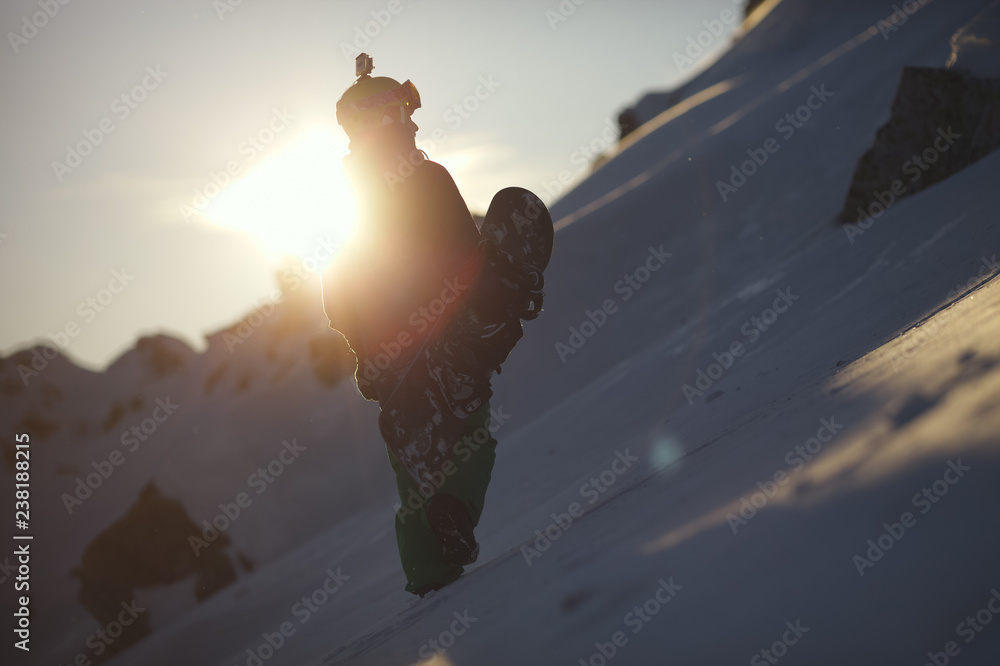 Fototapeta premium Silhouette of snowboarder on mountain slope against sunset background. Backcountry.