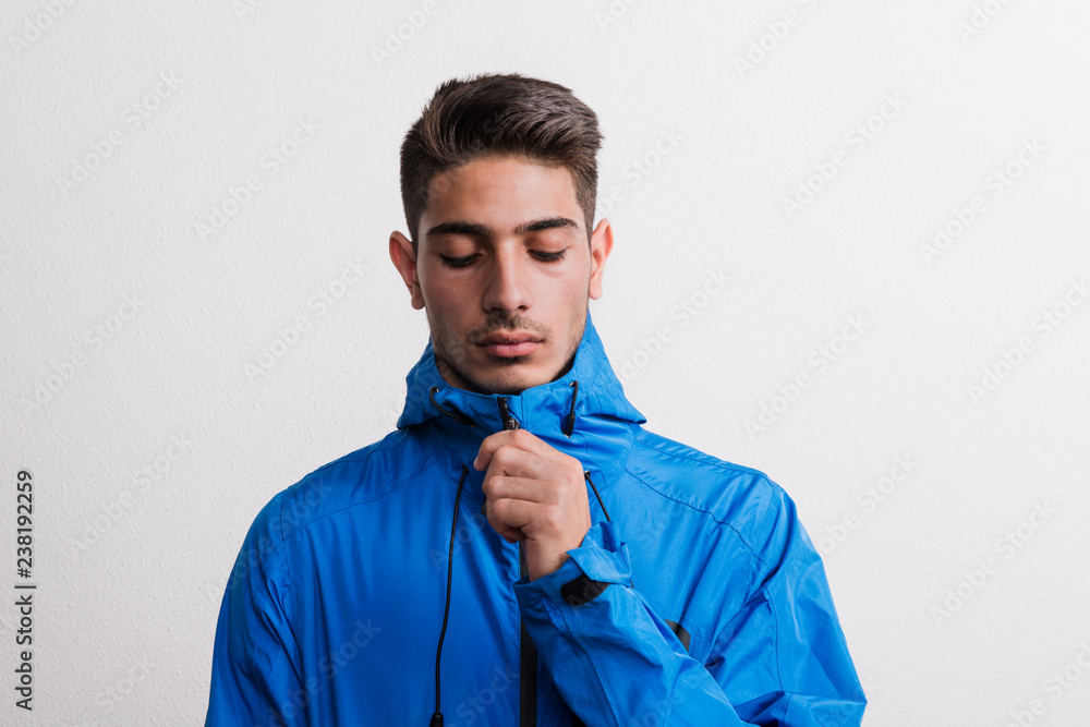 Portrait of a young serious hispanic man with blue anorak in a studio. Portrait of a young serious hispanic man with blue anorak in a studio.