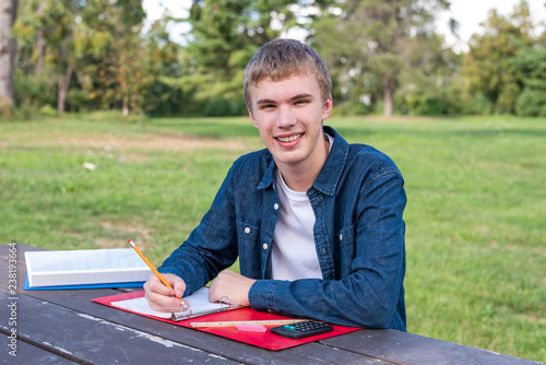 Canvas Print Happy teenager doing school work outdoors on a sunny afternoon.