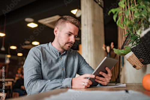 Young man using digital tablet in the cafe. Low angle view.