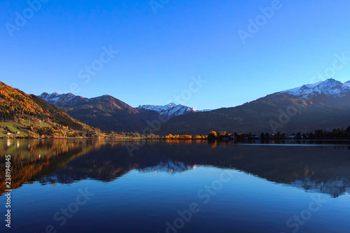 Beautiful view on the crystal clear water lake and snow covered top of mountains in Zell am See in Austria during late fall