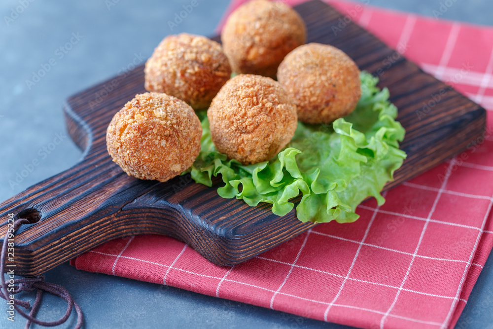 Falafel lies on a wooden cutting board. On the table lie tomatoes, cucumbers, lettuce, salad, dill, lemon, sour cream. Falafel lies on a wooden cutting board. On the table lie tomatoes, cucumbers, lettuce, salad, dill, lemon, sour cream.