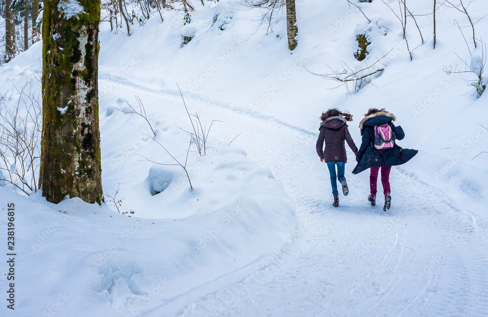 Zwei Mädchen laufen im verschneiten Wald
