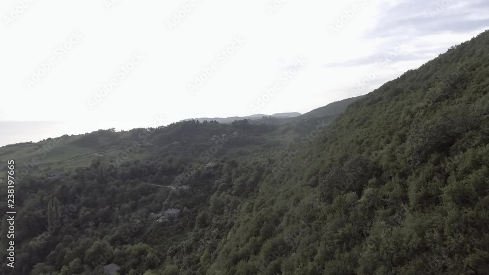 Spectacular landscape of Black Sea, Abkhazian long shore coast, green hill with small cave and cute valley surrounded by big trees, gardens and bushes shown on summer sunny day with blue sky. Spectacular landscape of Black Sea, Abkhazian long shore coast, green hill with small cave and cute valley surrounded by big trees, gardens and bushes shown on summer sunny day with blue sky.