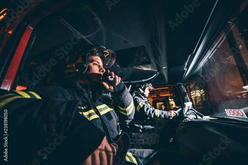 Fotografie Two Fireman Man posing inside the truck