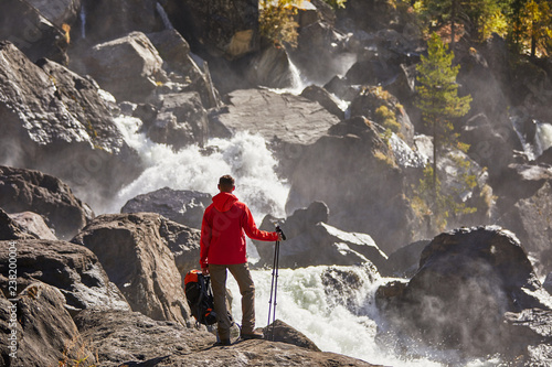 Happy man with backpack enjoying amazing waterfall Travel Lifestyle and success concept vacations into the wild nature