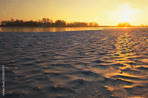 Winter landscape with frozen lake and sunset fiery sky. Composition of nature.