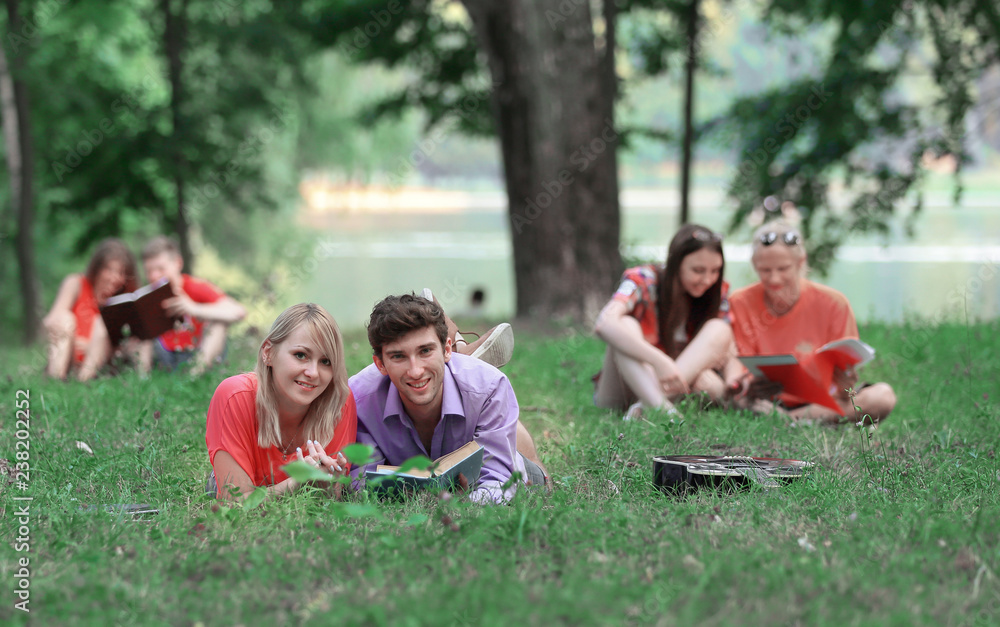 several pairs of students with books lying on the grass in the Park several pairs of students with books lying on the grass in the Park