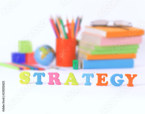 word strategy on blurred background of school supplies .photo with copy space