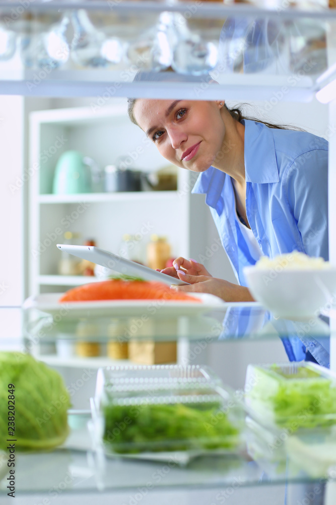 Portrait of female standing near open fridge full of healthy food, vegetables and fruits. Portrait of female standing near open fridge full of healthy food, vegetables and fruits.