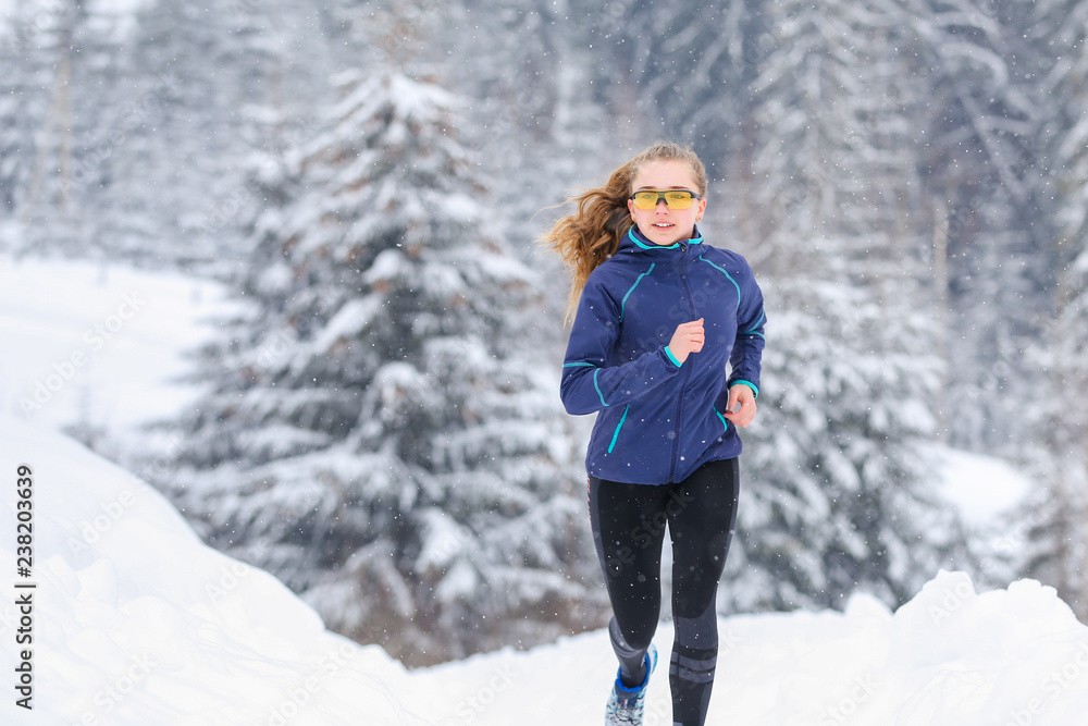 Teenage girl running on winter mountain trail