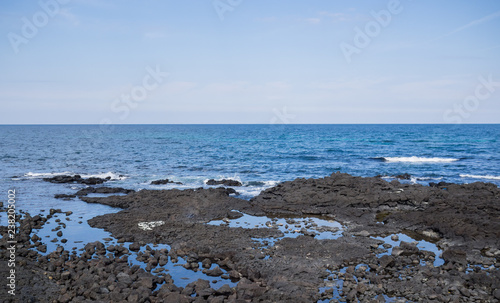 Beautiful blue sea with black sand beach and sky of Jeju island in Korean