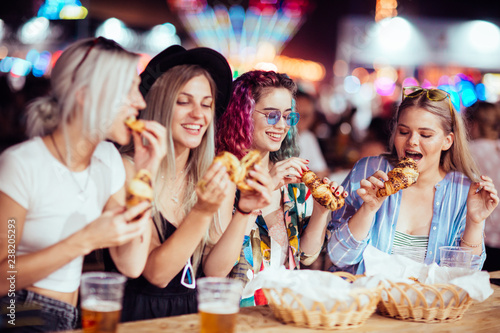 Female friends eating and drinking at music festival