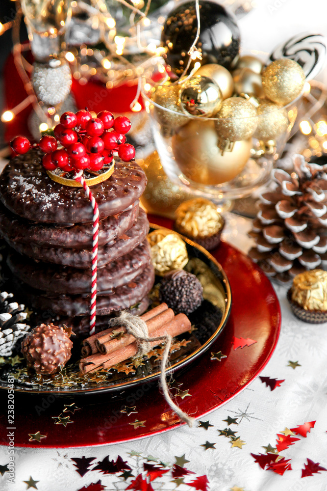 Christmas, xmas ginger bread with rowan, mountain ash and sweets, cookies on red plate, golden balls and confetti with cinnamon, chrismas cone Christmas, xmas ginger bread with rowan, mountain ash and sweets, cookies on red plate, golden balls and confetti with cinnamon, chrismas cone