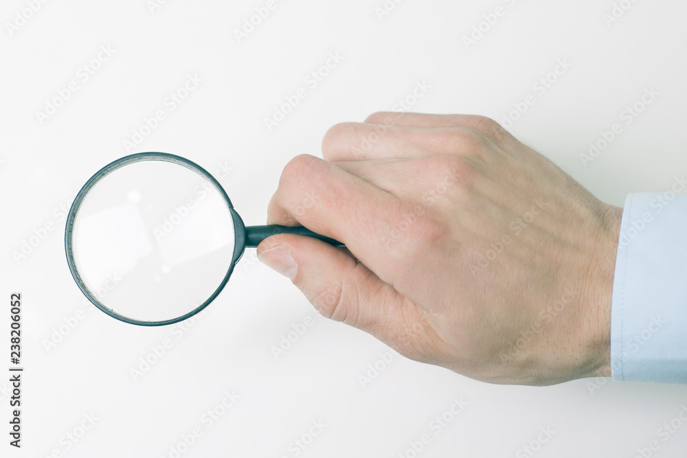 closeup.magnifier in the hand of businessman. isolated on a white background. closeup.magnifier in the hand of businessman. isolated on a white background.