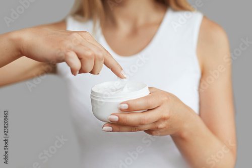 Fototapeta Naklejka Na Ścianę i Meble -  Closeup shot of woman hands holding cream and applying moisturizing hand cream. Beautiful female hands with cream. Hand Skin Care. A woman uses body lotion on your arms. Beauty And Body Care Concept