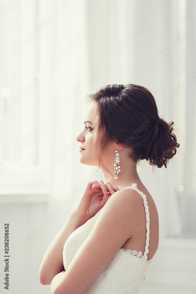 Beauty portrait of bride wearing fashion wedding dress with luxury hairstyle, studio indoor photo.
