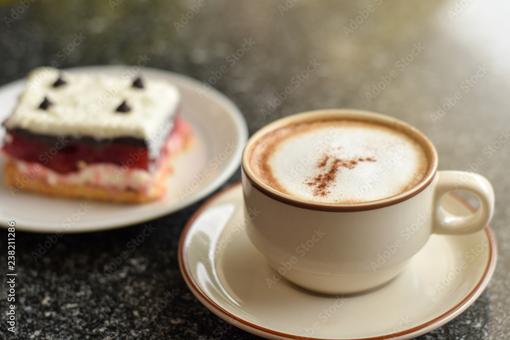 Cappuccino coffee served with raspberry layer cake on a cold morning at Cafe'. 