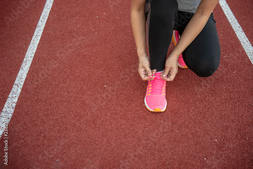 Athlete woman tying shoeslaces. at sport stadium, with copy space.