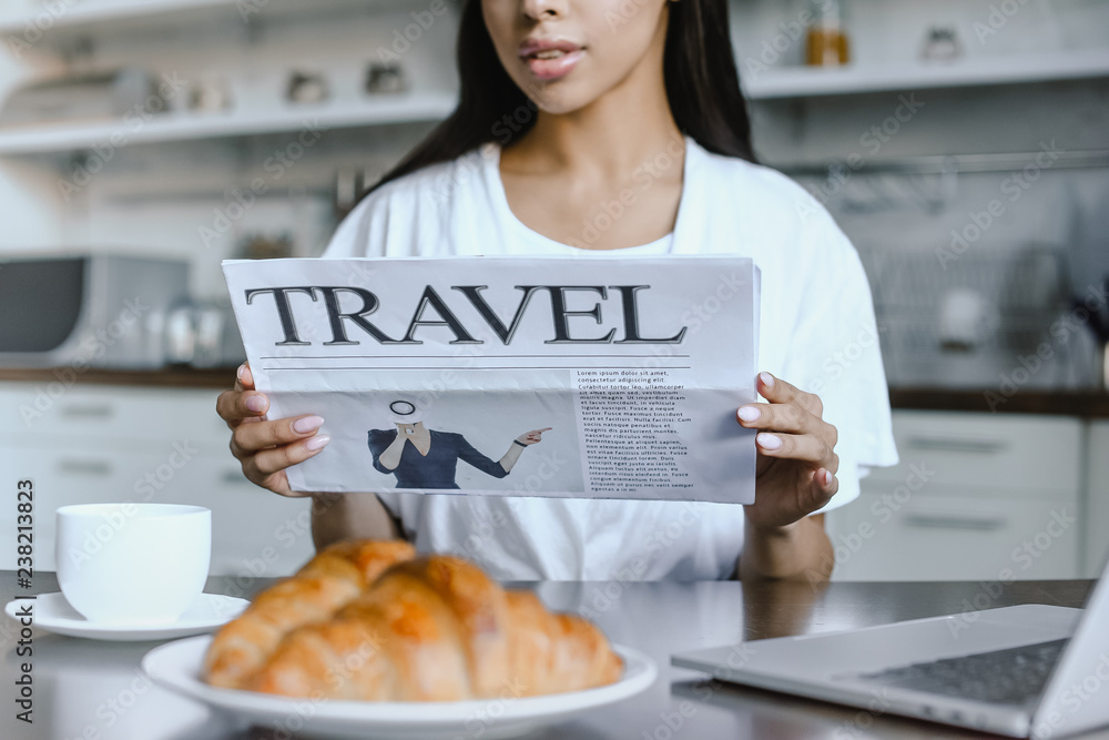 Φωτογραφία cropped image of mixed race girl in white robe reading travel newspaper in morni
