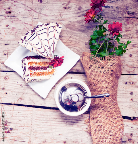 A piece of delicious cake with flowers on a wooden background